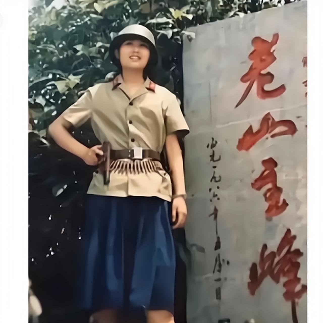 一名英姿飒爽的女兵站在老山主峰石碑前,全副武装:头戴钢盔,腰挂弹药