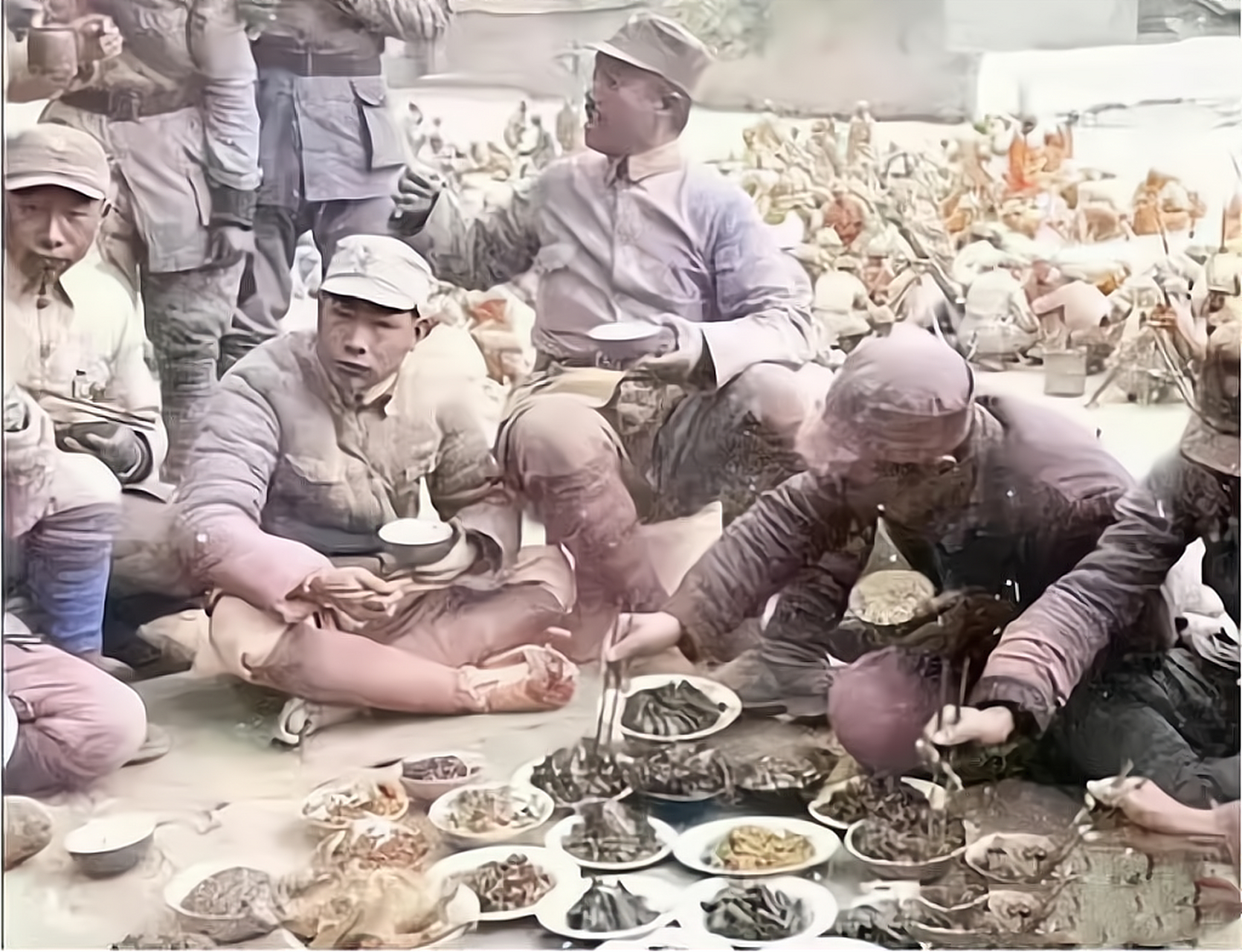 照片中,战士们席地而坐,匆匆忙忙地吃饭,地上的碗里摆着许多美味