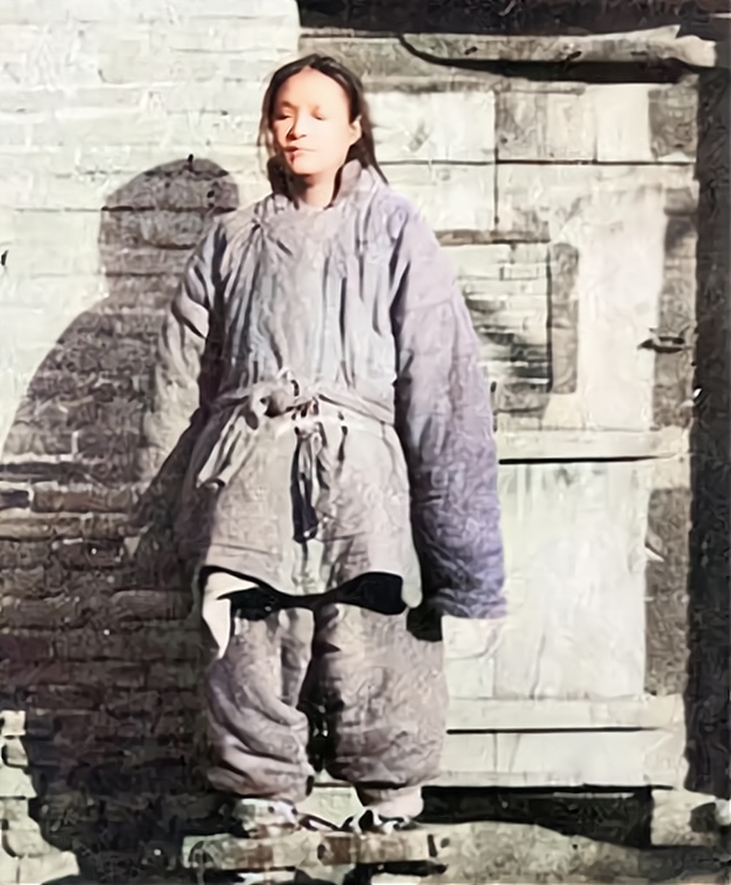 从照片中可以看出,这名女犯穿着一件破烂的棉衣,闭着眼睛.